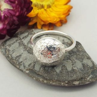 geometric pattern round domed pebble ring made of sterling silver. mounted on a silver band and can be worn with other stacking rings