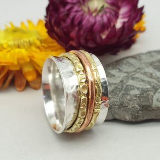 wide silver spinner ring with three patterned rotating bands in brass and copper