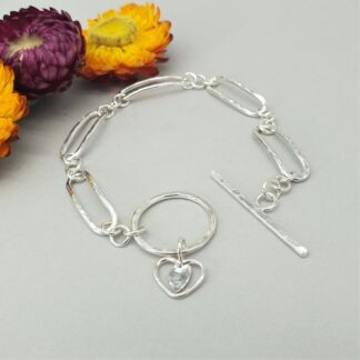 Silver oval textured link bracelet with large t-bar fastener and rustic heart charm