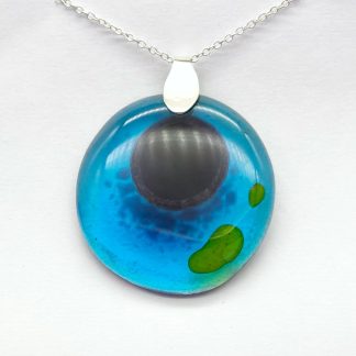 striking large round fused glass pendant in turquise with dark blue and green pattern. mounted on sterling silver bail and chain